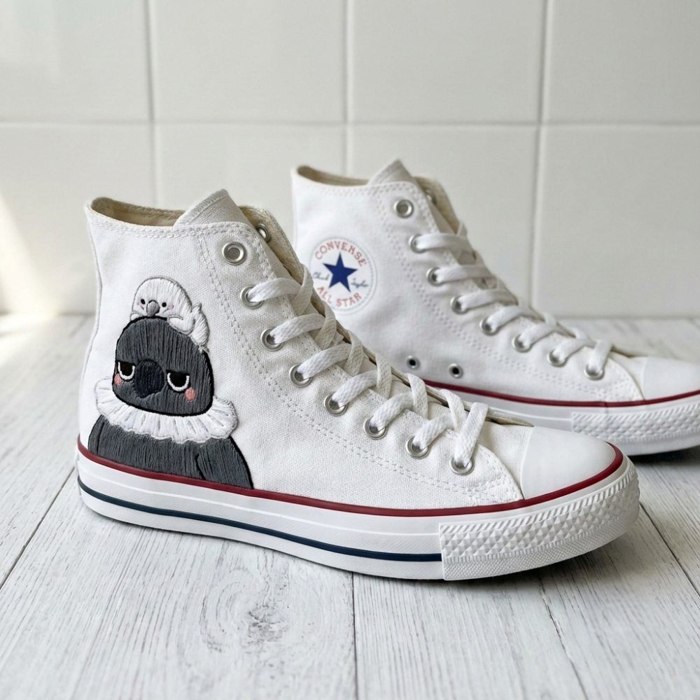 White high-top sneakers with a cartoon character design of Sylus from Love and Deepspace on a light wooden floor.